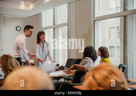 Businessman and woman talking to other their colleagues after giving a presentation within a meeting. Stock Photo