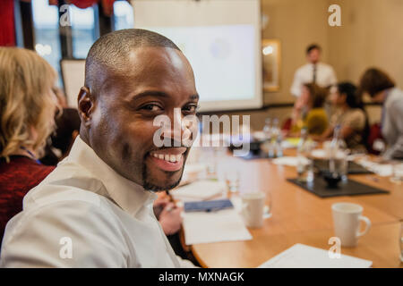 Mid-adult businessman turning in his seat, looking at the camera and smiling for a headshot. Stock Photo