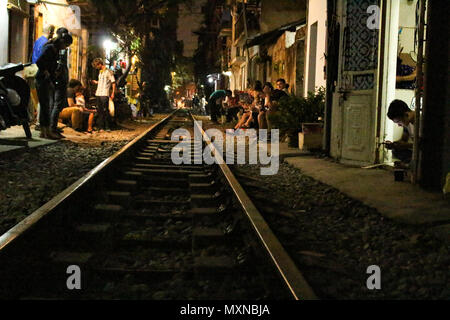 Hanoi, Vietnam - March 14, 2018: People sitting in Train street, one of the most recognizable touristic landmarks, at night Stock Photo