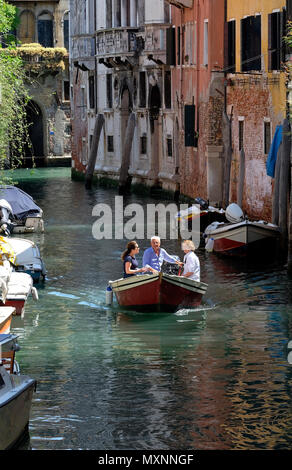 people in a small boat on canal in venice, italy Stock Photo