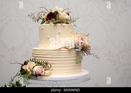 Champagne wedding cake with yellow and pink flower arrangements Stock Photo