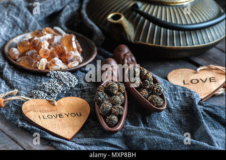 A Cup of brewed black tea. Two ceramic spatulas with caramel sugar and Rolled leaves in a large pearl. Chinese tea from Yunnan. Bi Lo Chun Stock Photo
