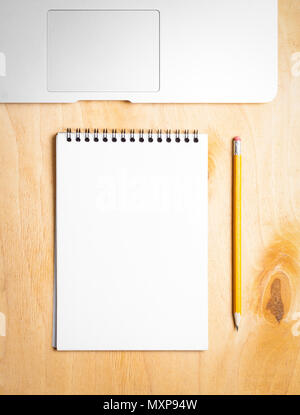 Business essentials. Top view of spiral blank notebook and laptop on wood desk background Stock Photo