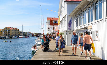 Smogen, Sweden - May 19, 2018: Travel documentary of everyday life and place. Tourists spending a day at the pier in the village. Boats moored just be Stock Photo