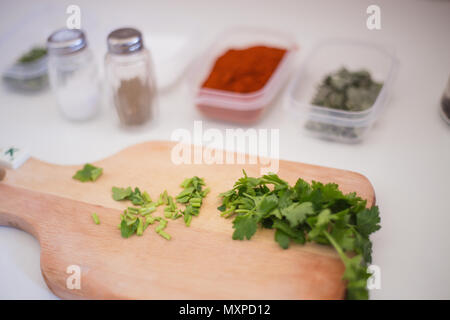 Green fresh parsley being prepared and cut for soup on the kitchen table and wooden cutting board with the seasonings aside salt and pepper for delici Stock Photo
