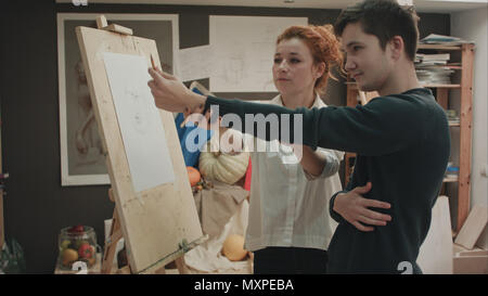 Female painter teaching young man how to draw classical face Stock Photo