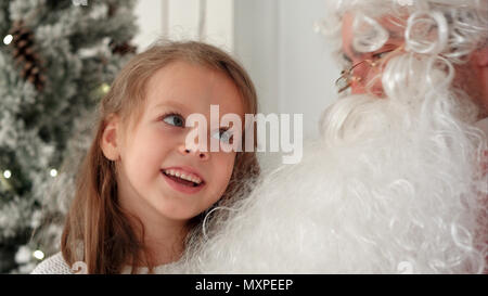 Cute little girl singing Christmas song together with Santa Claus Stock Photo