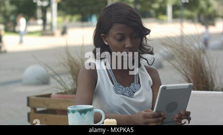 African young business woman working and using tablet in outdoor cafe Stock Photo