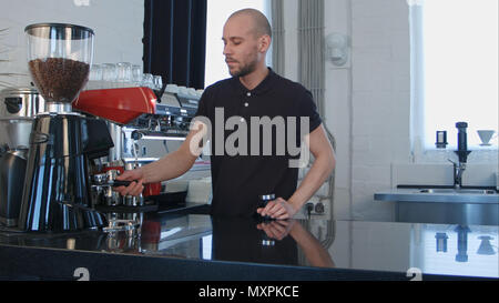 Male barista using the coffee machine preparing coffee for a client Stock Photo