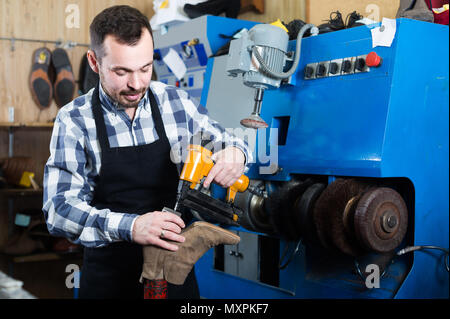 positive american  male worker fixing failed shoes in shoe repair workshop Stock Photo
