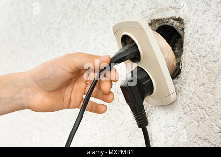 closeup of hand using broken dangerous electric socket Stock Photo
