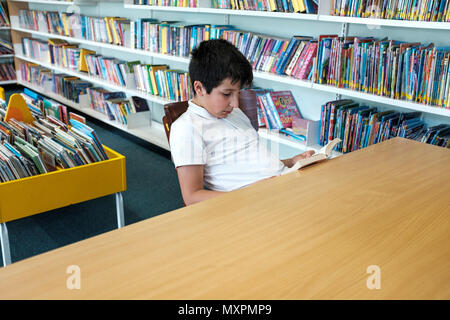 UK,Surrey,UK- 10 years schoolboy in public library Stock Photo