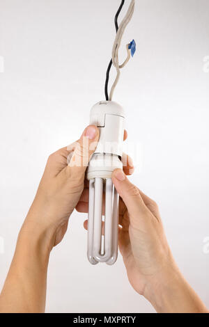 hands replacing energy saving light bulb in the socket Stock Photo