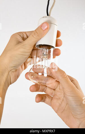 hands replacing incandescent light bulb in the socket Stock Photo