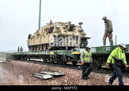 FORT CARSON, Colorado – A Soldier from 64th Brigade Support Battalion, 3rd Armored Brigade Combat Team, 4th Infantry Division, prepares to tie down an M88A2 recovery vehicle to a train car at Fort Carson, Colorado, Dec. 2, 2016. The train is the last of 12 hauling more than 2,000 pieces of rolling stock ultimately destined for Bremerhaven, Germany, where 3rd Brigade will receive its full set of ABCT equipment before onward movement to Poland for its deployment in support of Operation Atlantic Resolve. The arrival of the heavy brigade in January will mark the beginning of a continuous presence  Stock Photo