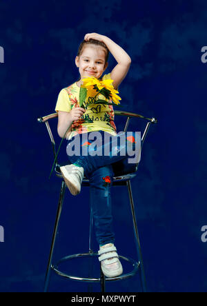 Studio shooting. Girl with a sunflower in her hand on a blue background. Stock Photo