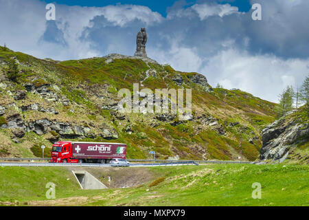 Red truck passing stone eagle statue the mountains on the Simplon Pass, between Switzerland and Italy Stock Photo