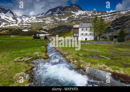 White house with red shutters and St Christopher, snowy weather in the mountains on the Simplon Pass, between Switzerland and Italy Stock Photo