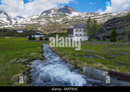 White house with red shutters and St Christopher, snowy weather in the mountains on the Simplon Pass, between Switzerland and Italy Stock Photo