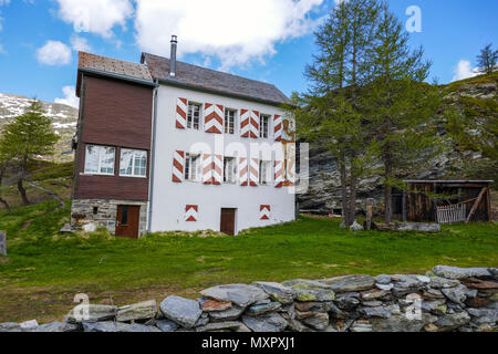 White house with red shutters and St Christopher, snowy weather in the mountains on the Simplon Pass, between Switzerland and Italy Stock Photo