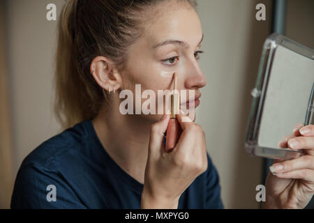 Close-up, side view of a young female adult applying make-up. Stock Photo