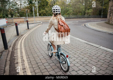 Rear view of an unrecognisable person cycling down the street on the way to work. Stock Photo