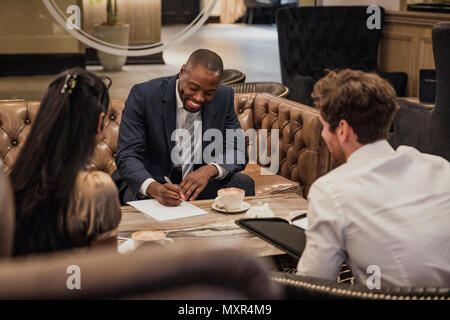 Rear view of three business people having a meeting in the reception of a building. Stock Photo