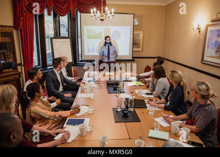 Businessman giving a presentation within a conference to a large group of business people. Stock Photo