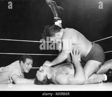 Max Baer (left), former world heavyweight boxing champion, referees a match between wrestlers Primo Carnera (on back), defeated world heavyweight boxing champion by Baer, and Jim Londos. Chicago, IL, 5/5/1950. Stock Photo