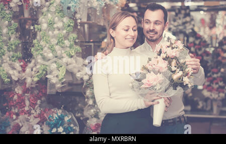 Young man buys a bouquet of flowers to a girl in a flower shop Stock Photo