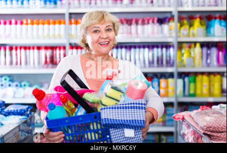Cheerful  smiling woman consumer with household chemical products in basket for cleaning Stock Photo