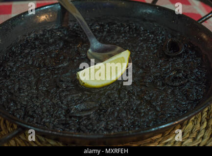 Rice paella with squid cooked in their ink in a restaurant in Alicante, Spain Stock Photo