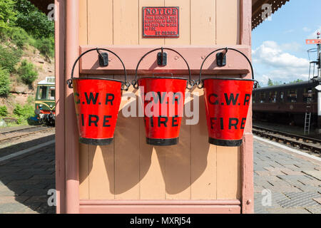 Red GWR vintage fire buckets on platform of vintage train station, Severn Valley steam railway. Old, antique fire fighting equipment. Stock Photo