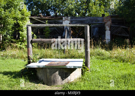 community well in Russian village in background of garden and poor houses Stock Photo