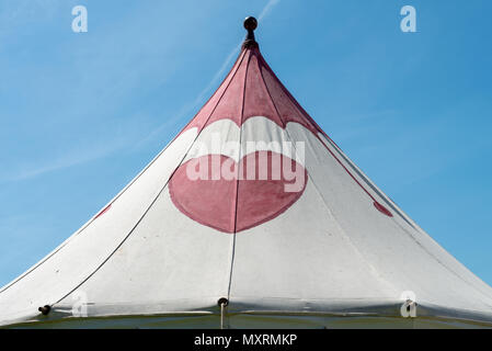 A canvas tent with a pink heart painted on it against a blue sky. Stock Photo