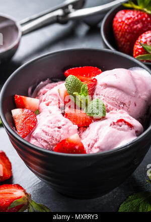 Strawberry ice cream with fresh berries in black bowl. Close up. Stock Photo