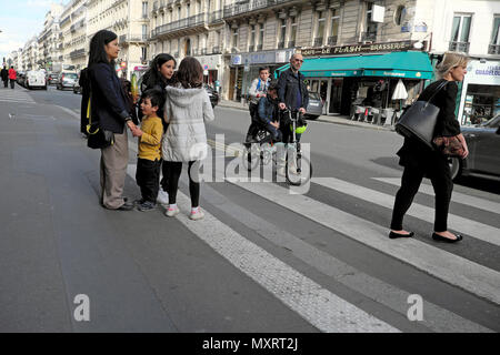 Parents and children going home on an afternoon after the school day walking and on bike near a pedestrian crossing  in Paris France  KATHY DEWITT Stock Photo