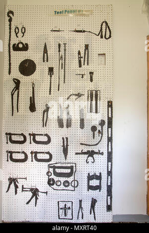 Outline of auto body shop tools on peg board inside abandoned prison. Stock Photo