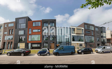AMSTERDAM, NETHERLANDS - MAY 30: (EDITORS NOTE: Image is a panoramic composite.) Finished modern houses stand next to buildings under construction at Bert Haanstrakade Street of IJburg on May 30, 2018 in Amsterdam, Netherlands. When the project will be finished, the neighbourhood will have 18,000 homes for 45,000 residents. Stock Photo