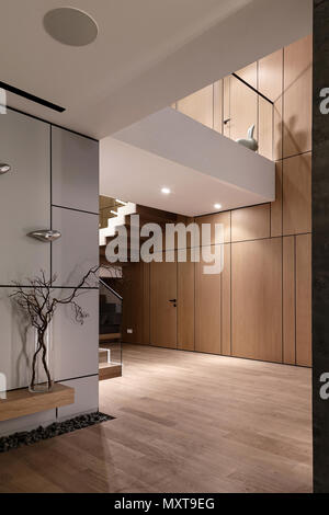 Trendy modern interior with wooden walls and a stair with wooden rungs and a glass railing. There are luminous lamps, white wall decorated with chrome Stock Photo