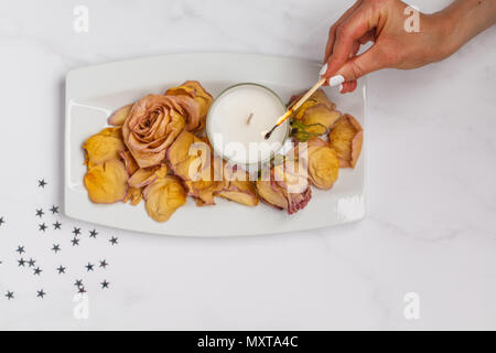 Beautiful white flat lay with a candle and dried rose petals. Top view, white background, flat lay concept Stock Photo