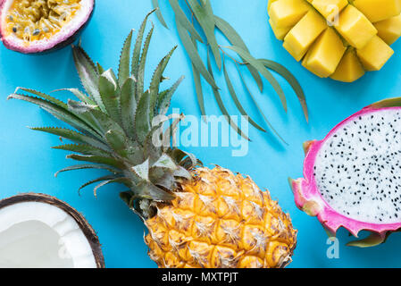 Thai tropical fruits on blue background. Pineapple, mango, pitaya, coconut and passion fruit flat lay Stock Photo