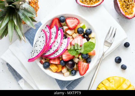 Tropical fruit salad with dragon fruit and mango in a bowl. Colorful exotic fruit salad on white background, table top view Stock Photo