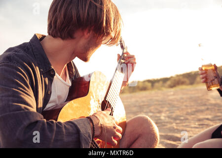 Photo of young caucasian man outdoors on the beach play on the guitar. Stock Photo