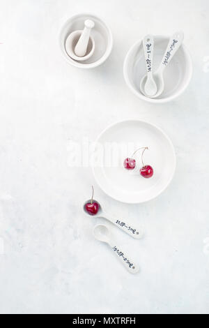 Minimalist empty porcelain dishes on a white stone background with copy space. Cherry pie baking concept. Stock Photo