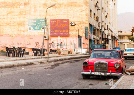 Aqaba, Jordan - May 18, 2018: Red abandoned Mercedes-Benz W110 190, midsize automobile stands on dirty roadside in Aqaba city