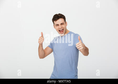 Portrait of an excited young man showing thumbs up gesture isolated over white background Stock Photo