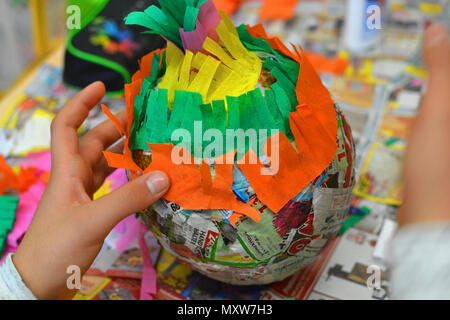 Children hands are making a pinata with colorful paper and glue. Stock Photo