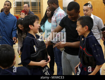 CAMP KENGUN, Kumamoto City, Kumamoto Prefecture, Japan – Spc. Shamell D. Martin, military police officer with the 247th MP Detachment, helps a Japanese child stuff cookies and drinks into his Kendo armor.  The soldiers attended Kendo training at the Kumamoto city police station to foster good relations between the U.S. military and the Japanese people during Yama Sakura 71. Exercise Yama Sakura 71 is an annual command post exercise co-sponsored by U.S. Army Pacific and the JGSDF at Camp Kengun from Dec. 1-13. The purpose of the exercise is to enhance U.S. and Japan’s combat readiness and inter Stock Photo