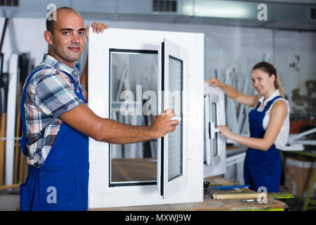 Portrait of  happy male worker with finished plastic window in assembly shop Stock Photo